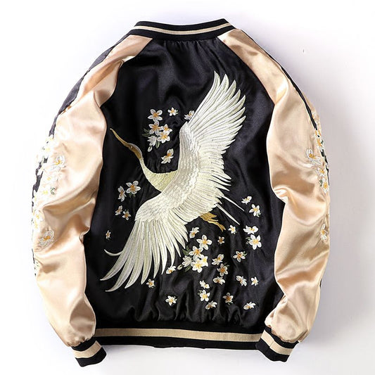 Elegant bomber jacket featuring a beautifully embroidered white crane in flight, surrounded by small white flowers, on a black and gold satin background